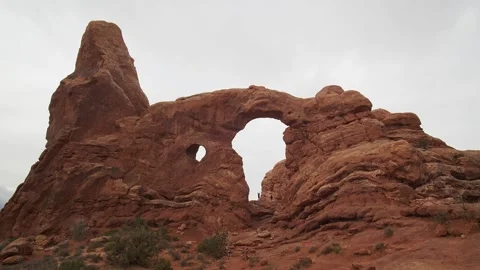 Tourists hike through the windows of Landscape Arch in the desert. Video stock 333991572