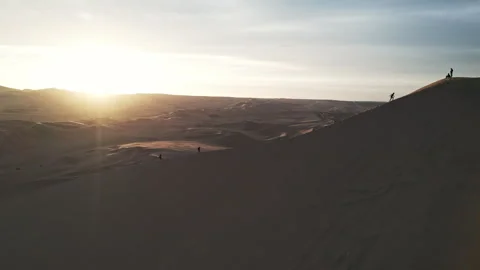 Tourists hiking dune at peruvian desert sunset Stock Footage 247724097