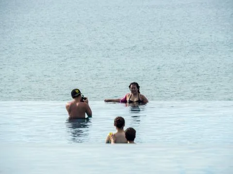 Tourists in infinity pool with ocean background Stock Photos