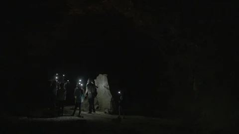Tourists inspecting a rock inside a cave Stock Footage 87613292