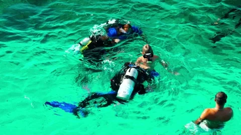 Tourists with an instructor scuba dive in the Red Sea over a coral reef. Video stock 324897418