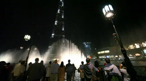 Tourists looks at fountains show near night skyscraper Burj Khalifa in Dubai, Stock Footage