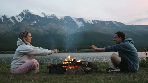 Tourists made a fire in the evening in the mountains and warmed their hands. Video stock 280726286