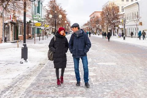 Tourists man and woman walking along city street in winter cloudy day. People Stock Photos