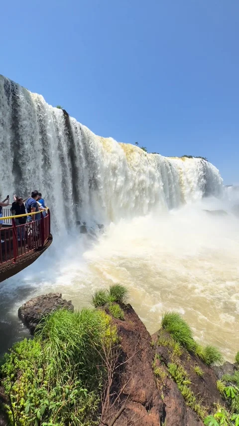 Tourists observing a powerful waterfall from a viewing platform on a sunny day. Stock Footage 276618655