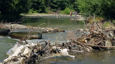 Tourists pass polluted mountain river. Plastic rubbish on branches Stock Footage 78000894