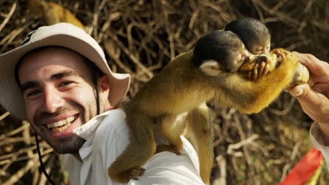 Tourists play with squirrel monkeys during a boat trip at Yacuma river, Bolivia Stockbeeldmateriaal 125486465