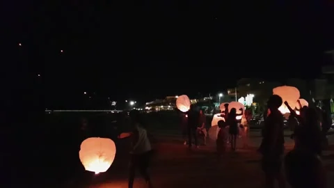 Tourists playing with sky lanterns at night beach party in italy 库存影片 279907404