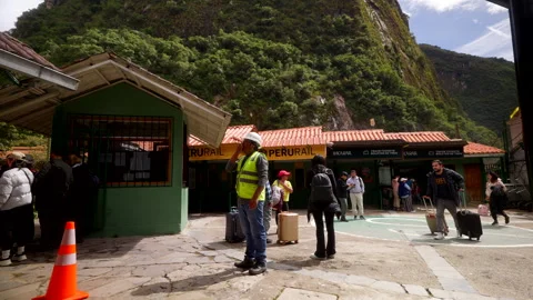 Tourists queue with luggage at train station gateway to mountain ruins Stock Footage 327853793