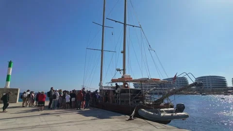 Tourists queue on the sunny Marfa waterfront beside the boats and yachts Stock Footage 338037336