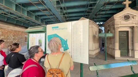 Tourists reading an information map at Montmartre cemetery entrance in Paris Stock Footage 337783614