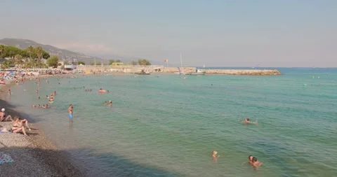 Tourists relaxing on the pebble beach during summer in Roquebrune-Carnolès Stock Footage 342298880