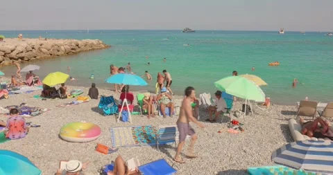 Tourists relaxing on the pebble beach during summer in Roquebrune Carnolès Stock Footage 342583556