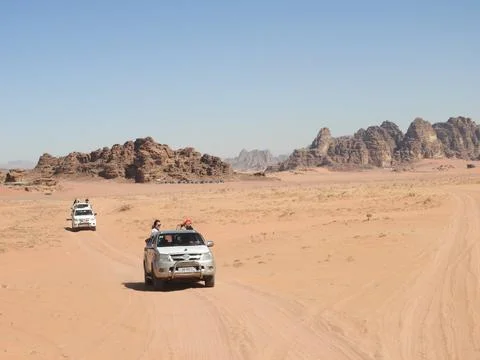 Tourists in off-road vehicles explore the vast, arid desert landscape of Wadi Stock Photos