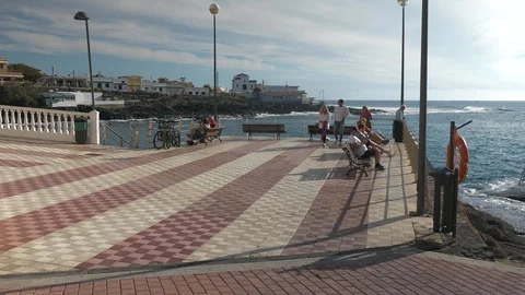 Tourists Sitting On Benches At seafront La Caleta Tenerife Spain Stock Footage 104394203