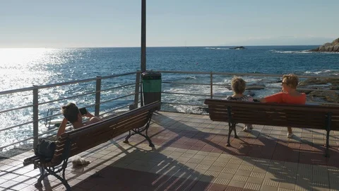 Tourists Sitting On Benches At seafront La Caleta Tenerife Spain Stock Footage 104394423