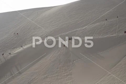 Tourists sledding on Singing Sand Mountain, Taklamakan Desert, Dunhuang, Chin Stock Photos