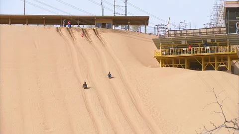 Tourists slides down with a sand boarding on the sand dune in Gobi desert Stockbeeldmateriaal 88337306