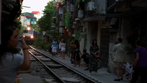 Tourists stand in front of an approaching train at Train Street in Hanoi Stock Footage 118750104