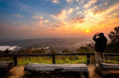 Tourists standing on the edge of the cliffs taking pictures of the sunrise. Stock Photos