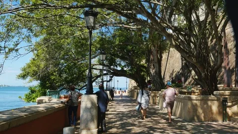 Tourists stroll tree covered walk along the wall of old San Juan Puerto Rico Stock Footage 73299546