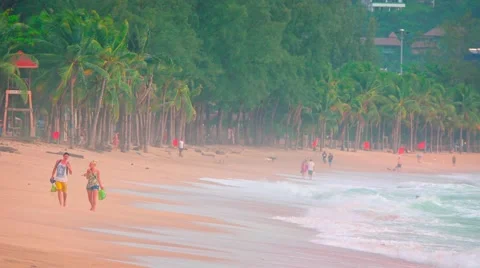 Tourists strolling along a stretch of the sandy, tropical, Kamala Beach Stockbeeldmateriaal 55381956