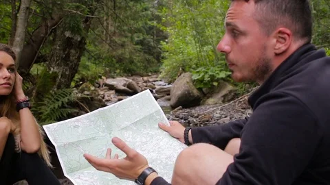 Tourists study the map of the area in a camping near the creek Stock Footage 78642741