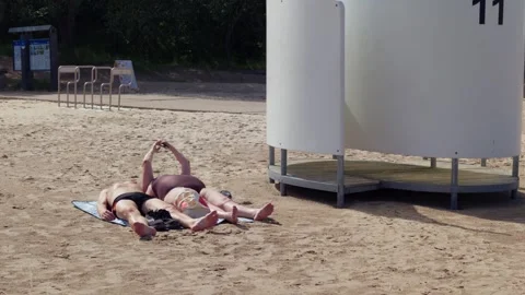 Tourists sunbathing on sandy beach beside changing cabin in Jurmala resort Stock Footage 344356848