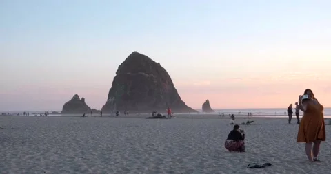 Tourists taking photos at haystack rock with sunset, Cannon Beach, Oregon - 4K Stock Footage 219699853