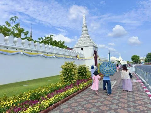 Tourists using umbrellas while walking under the summer sun outside Stock Photos