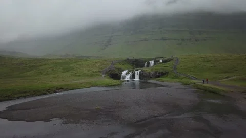 Tourists view a small waterfall below a foggy mountain Stockbeeldmateriaal 166846928