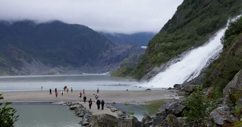 Tourists visit the base of Nugget Falls on a rainy overcast Alaska day Stock Footage 208548676