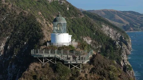 Tourists visiting Nugget Point lighthouse viewpoint on coastal cliffs Stock Footage 330950063