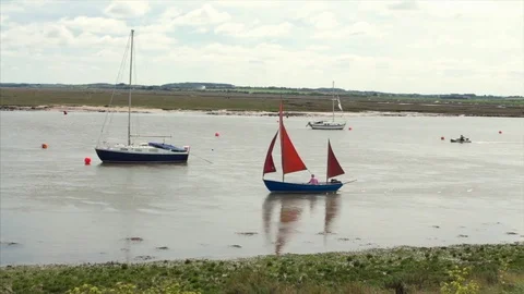 Tourists walk along the coast while a yacht sails by on a sunny day 스톡 동영상 76434883