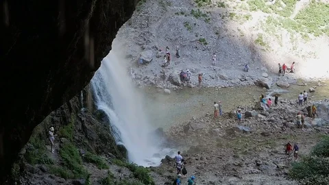 Tourists walk around the waterfall Stock Footage 80558339