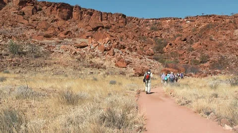 Tourists walk in front of table mountain at twyfelfontein Stock Footage 22645009