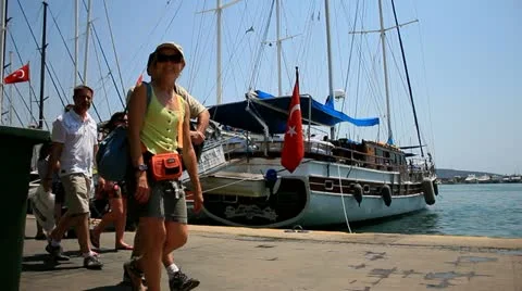 Tourists walk past Boats and Ferries on Pier of Bodrum, Turkey Stock Footage