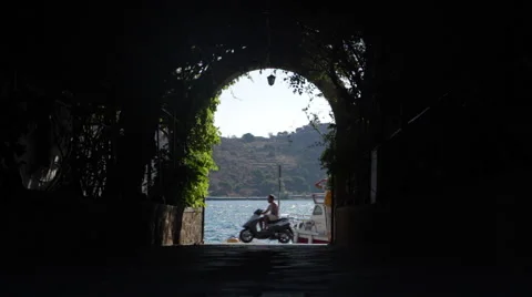 Tourists walk through a leafy arch tunnel to the harbour Vidéo 68404164