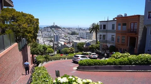 Tourists walking besides and driving along Lombard street in San Francisco Stock Footage