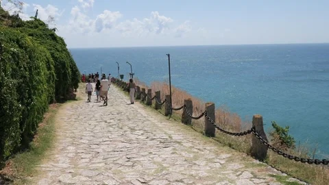 Tourists walking on a cobblestone path overlooking the sea Vídeos de archivo 342649930