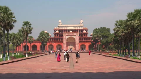 Tourists walking on pathway towards Akbars Tomb gateway in Sikandra Agra India Stock Footage 343883956