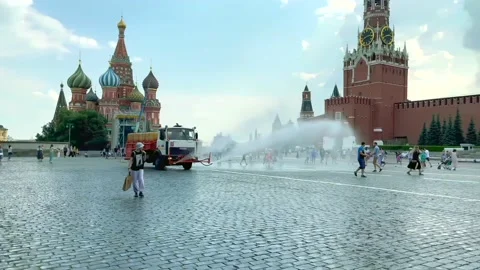 Tourists walking on Red Square. City service vehicles spray water on the streets Stock Footage 201952992
