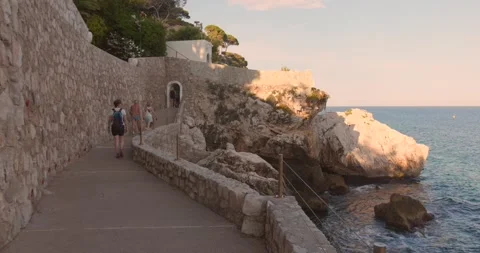 Tourists Walking on Stone Coastal Path Overlooking Sea at Cap d'Ail, French Stock Footage 343463820