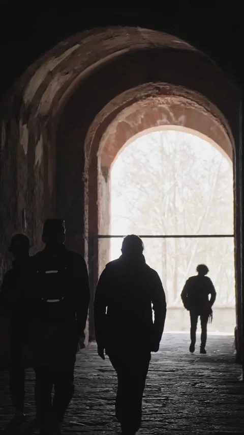 Tourists walking through an ancient stone tunnel towards the end, handheld Stock Footage 338315791