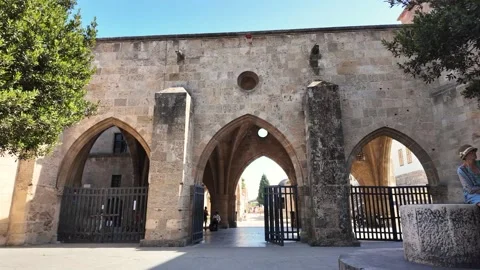 Tourists walking through medieval stone gate in Old Town Rhodes Greece Stock Footage 340575929