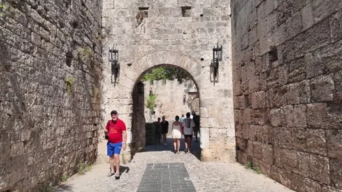 Tourists walking through stone archway in Old Town Rhodes Greece Stock Footage 340575923