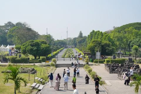 Tourists walking on a wide pathway inside the Prambanan temple park. Stock Photos