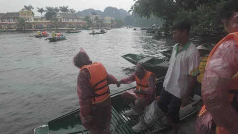 Tourists wearing rain jacket getting on a boat ride at Tam Coc Stock Footage 290076706