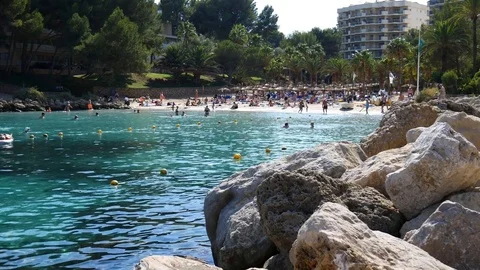 Tourists on white sandy beach next to clear blue sea in Cala Vinyes Mallorca Video stock 81048976