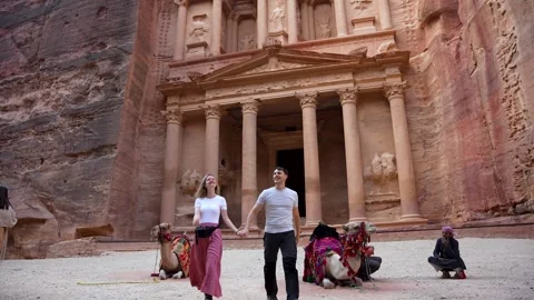 Tourists, Working Camels and Guide before Ancient Treasury Facade Stock Footage 346744822
